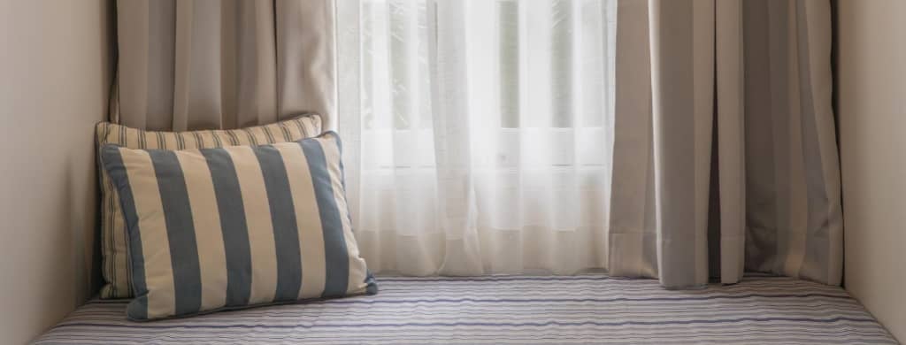 DIY curtains in a window seat with striped pillows and seat cushion